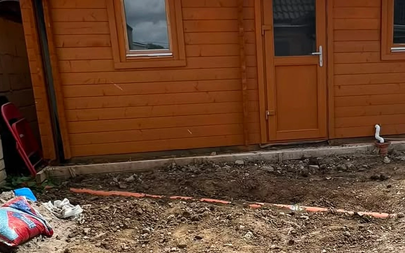 Bare ground in front of the garden cabin before the patio was laid